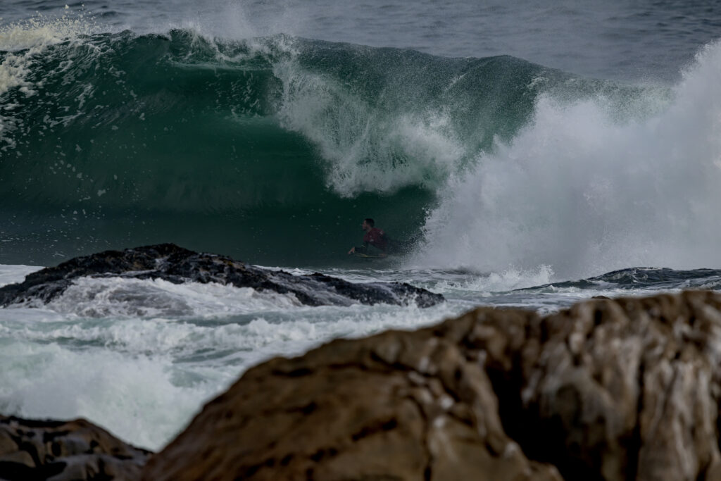 Boadyboarder riding on green wave face.