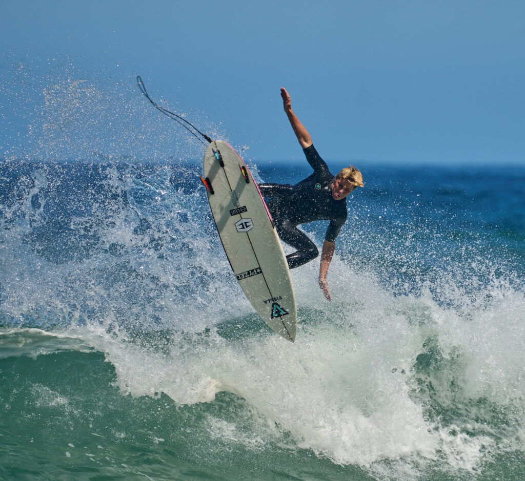 Surfer does a 360 and gives a glimpse of bottom deck of his Pyzel surfboard